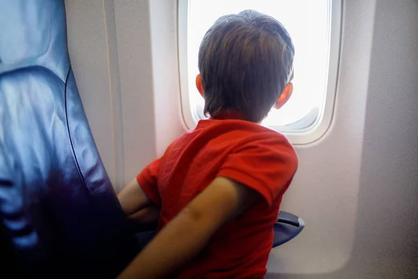 Kleine jongen jongen op zoek buiten vliegtuig venster tijdens vlucht op vliegtuig. — Stockfoto