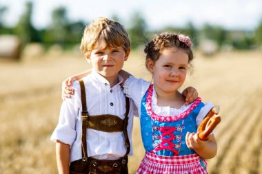 Buğday tarlasında geleneksel Bavyera kostümlü iki çocuk.
