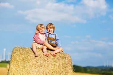 İki küçük çocuk çocuklar, İkizler ve kardeşleri saman yığını üzerinde sıcak yaz gününde oturuyor