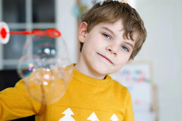 Happy little school boy playing with soap bubbles at home. Kid having fun. — Stock Photo, Image