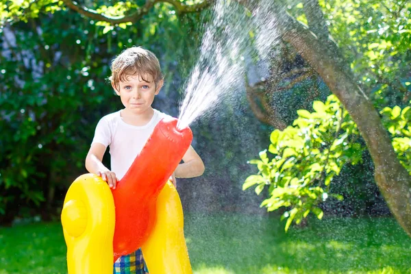 Kleiner Junge spielt mit Gartenschlauch-Wassersprenger — Stockfoto