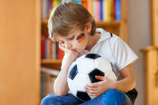 Sad and not happy little kid with football about lost football or soccer game. child after watching match on tv — Stock Photo, Image