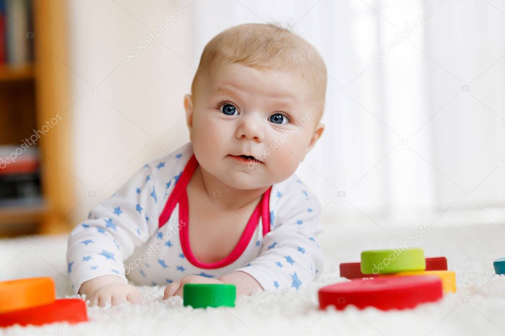 Cute baby girl playing with colorful wooden rattle toy