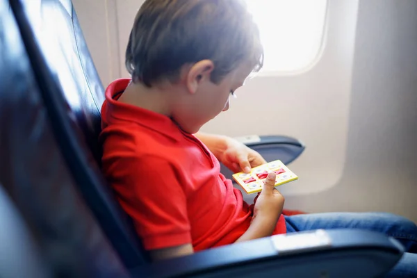 Little kid boy playing tic tac toe game during flight on airplane. — Stock Photo, Image