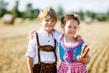 Buğday tarlasında geleneksel Bavyera kostümlü iki çocuk.