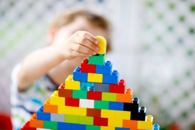 Küçük sarışın çocuk ve çocuk bir sürü renkli plastik blokla oynuyorlar..