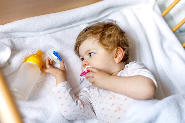 Schattig klein meisje met flesje met formule mild en drinken. Kind in kinderbedje voor het slapen gaan — Stockfoto