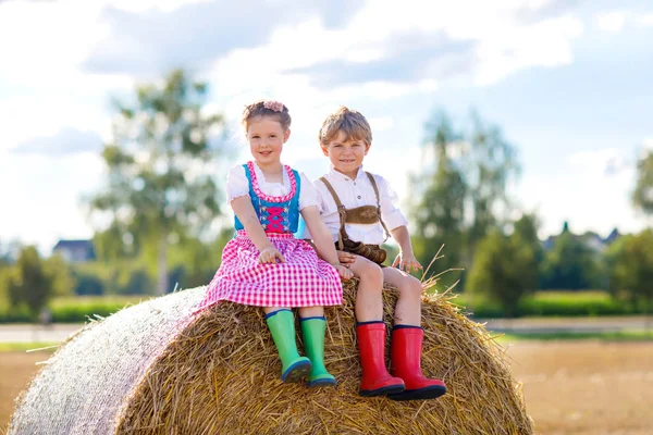 Dvě děti, chlapec a dívka v tradičních bavorských kostýmech v pšeničném poli — Stock fotografie