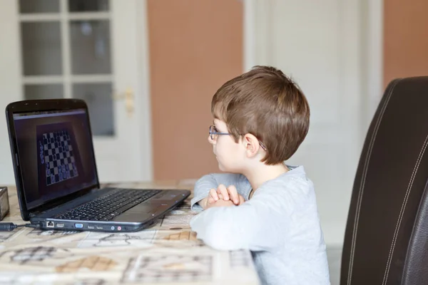 Kid boy med glasögon spela online schack brädspel på datorn — Stockfoto