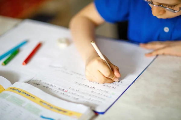Крупный план маленького мальчика в очках дома, делающего домашнее задание, пишущего письма красочными ручками . — стоковое фото