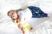 Roztomilý rozkošný holčička 6 měsíců spí mírové v posteli