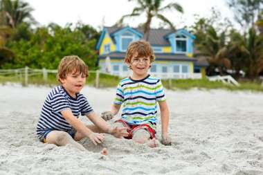 İki küçük çocuk tropik sahilde eğleniyor.