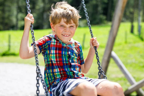 Grappige jongen jongen plezier met keten schommel op buitenspeeltuin terwijl wordt nat met water bespat — Stockfoto