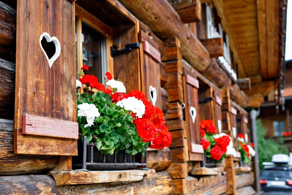 Típica ventana de madera bavariana o austriaca con flores de geranio rojo en casa en Austria o Alemania — Foto de Stock