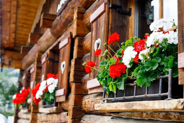 Fenêtre typique bavaroise ou autrichienne en bois avec des fleurs de géranium rouge sur la maison en Autriche ou en Allemagne — Photo