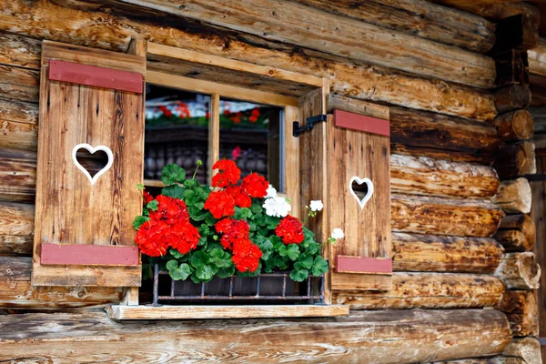 Fenêtre typique bavaroise ou autrichienne en bois avec des fleurs de géranium rouge sur la maison en Autriche ou en Allemagne — Photo