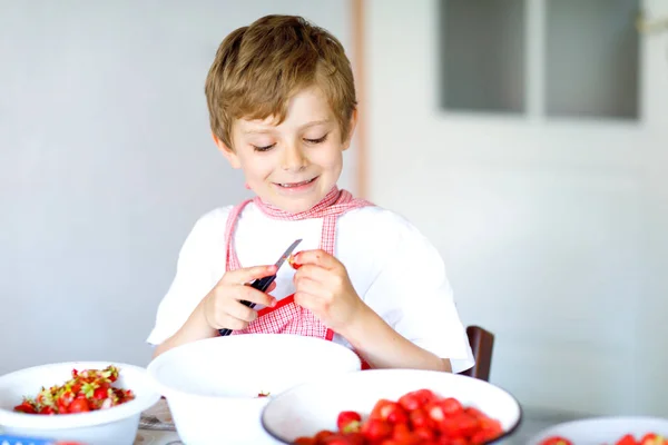 Kleine blonde jongen jongen te helpen en aardbeienjam maken in de zomer — Stockfoto