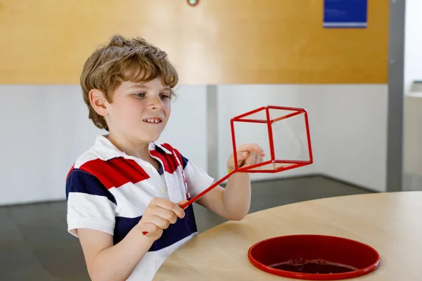 Szczęśliwy chłopiec bawiący się z budowaniem i tworzeniem figur geometrycznych, nauką matematyki i geometrii — Zdjęcie stockowe