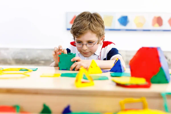 Garçon heureux enfant avec des lunettes s'amuser avec la construction et la création de figures géométriques, l'apprentissage des mathématiques et de la géométrie — Photo