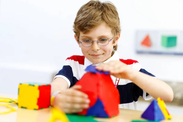 Šťastný chlapec s brýlemi baví s budováním a vytvářením geometrických figurek, učení matematiky a geometrie — Stock fotografie
