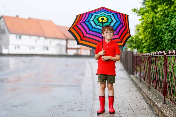 Petit garçon portant des bottes de pluie rouge et marchant avec parapluie — Photo