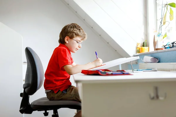 Ragazzino carino con gli occhiali a casa a fare i compiti, scrivere lettere con penne colorate . — Foto Stock