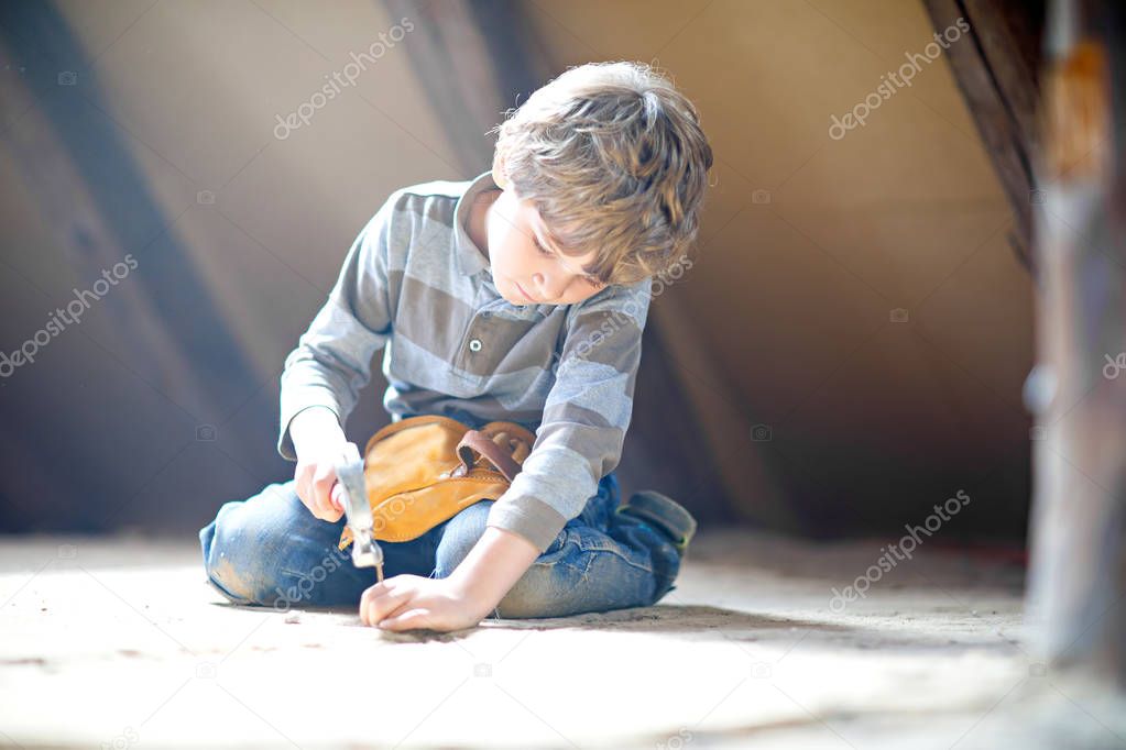 Little kid boy helping with toy tools on construciton site.