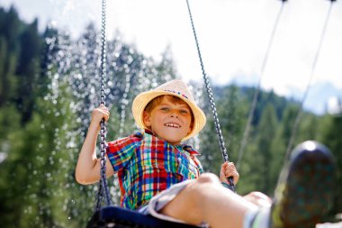 Komik çocuk çocuk iken ıslak olduğu su ile sıçrayan ile zincir salıncak açık sahada eğleniyor