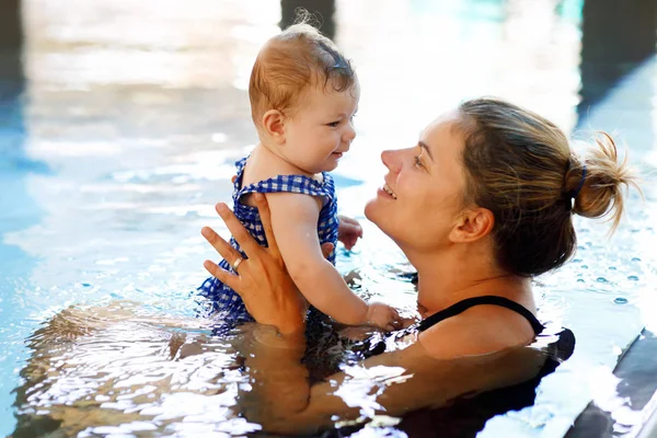 Happy mother swimming with cute adorable baby girl daughter in swimming pool spending spa vacations — Stock Photo, Image