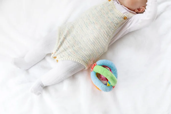 Gros plan du corps et des jambes du bébé avec beaucoup de jouets colorés . — Photo