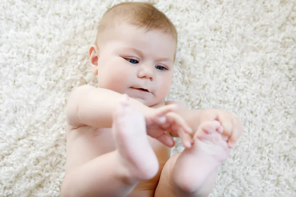 Söt baby flicka som leker med egna fötter. — Stockfoto