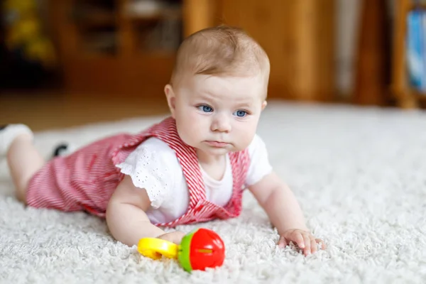 Lindo bebé jugando con colorido juguete educación sonajero. Lttle chica mirando a la cámara y arrastrándose — Foto de Stock