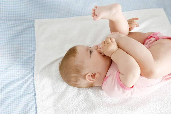 Niedliches Baby, das Füße in den Mund nimmt. entzückende kleine Mädchen lutschen Fuß. — Stockfoto