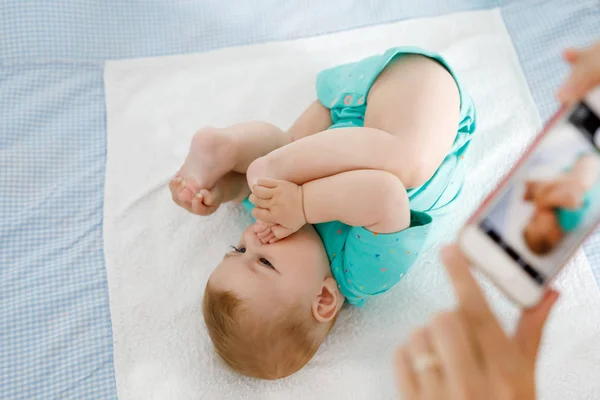 Pais tirando fotos de um bebê com smartphone. Adorável recém-nascido tomando pé na boca — Fotografia de Stock
