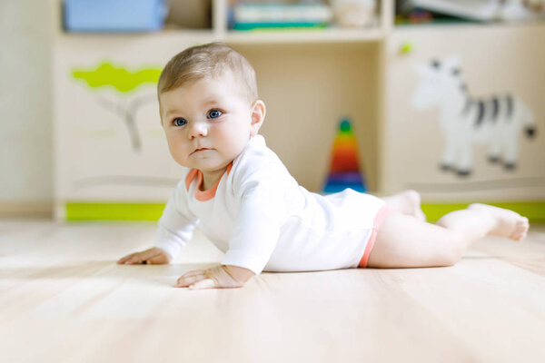 Cute baby girl learning crawling and sitting in children room