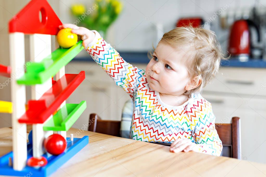 Adorable cute beautiful little baby girl playing with educational toys at home or nursery.