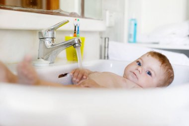 Alarak şirin bebek yıkama lavabo banyo ve musluk suyu yakala.