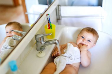Alarak şirin bebek yıkama lavabo banyo ve musluk suyu yakala.