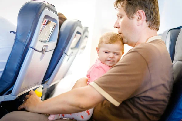 Jonge moe vader en dochter met huilende baby tijdens vlucht op vliegtuig op vakantie te gaan — Stockfoto