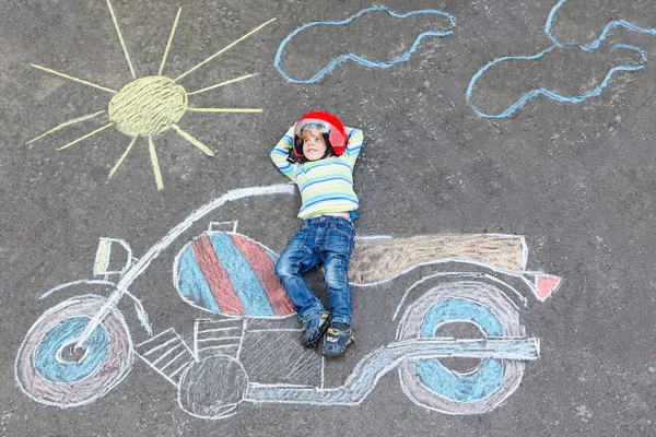 Little child in helmet with motorcycle picture drawing with colo — Stock Photo, Image