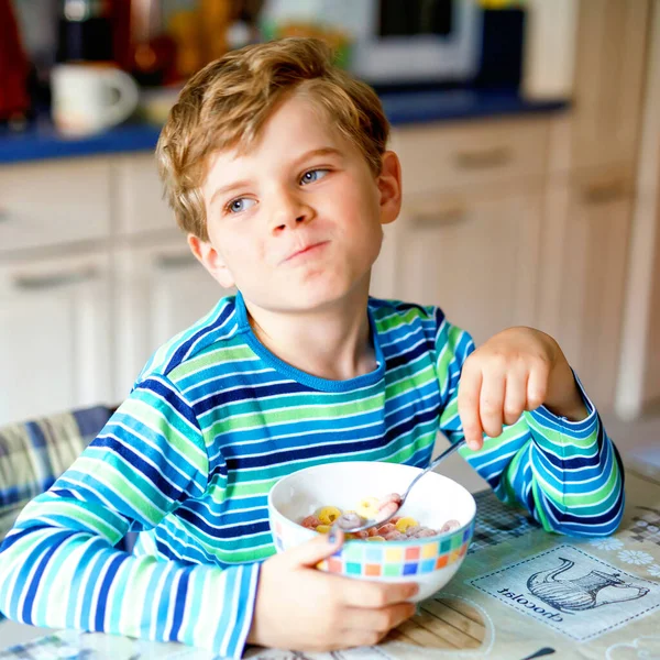 愛らしい小さなブロンド学校子供男の子朝食や昼食のため牛乳や果実が付いている穀物を食べるします。健康的な食事、学童の子供のため。学校の食堂や家庭で — ストック写真