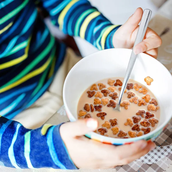 Zbliżenie z rąk dziecko jedzenie domowe zboża na śniadanie lub lunch. Zdrowe jedzenie dla dzieci. W przedszkolu, stołówki szkolne lub w domu. Zbliżenie: miski z mlekiem i musli. Dziecko gospodarstwa łyżka. — Zdjęcie stockowe