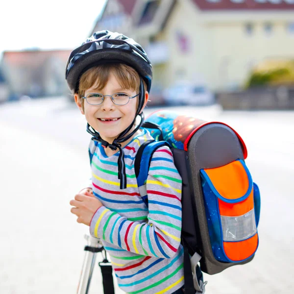 Niño activo de la escuela en casco de seguridad que monta con su scooter en la ciudad con mochila en el día soleado. Niño feliz en ropa colorida en bicicleta de camino a la escuela. Manera segura para los niños al aire libre a la escuela —  Fotos de Stock