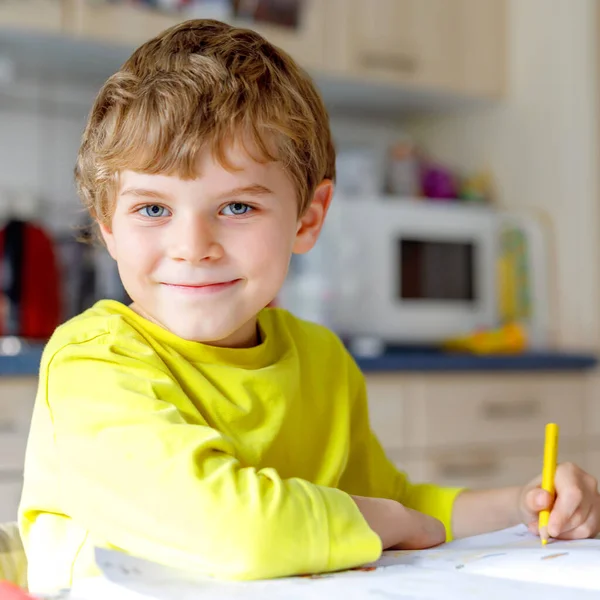 Portrait de mignon écolier garçon à la maison faire des devoirs. Petite écriture d'enfant concentrée avec des crayons colorés, à l'intérieur. École primaire et éducation. Enfant apprenant à écrire des lettres et des chiffres . — Photo