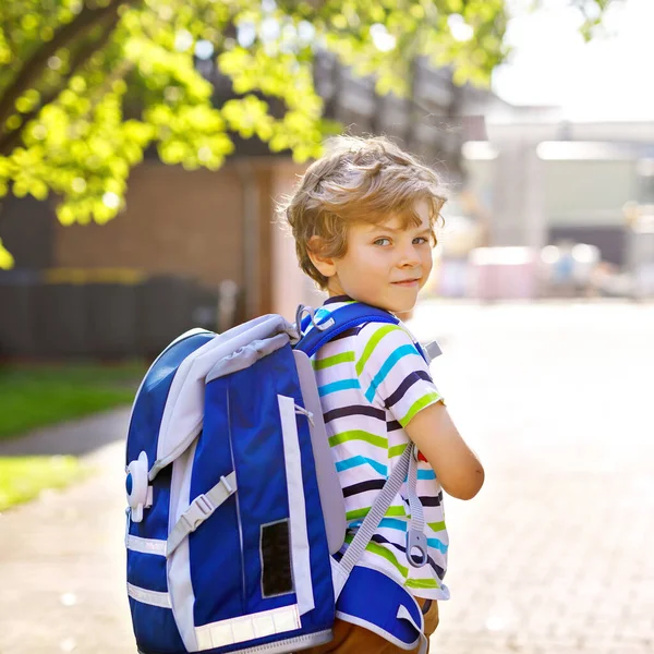 Glücklicher kleiner Junge mit Brille und Rucksack oder Schulranzen an seinem ersten Schul- oder Kindergartentag. Kind an warmen, sonnigen Tagen im Freien, Zurück zum Schulkonzept. — Stockfoto