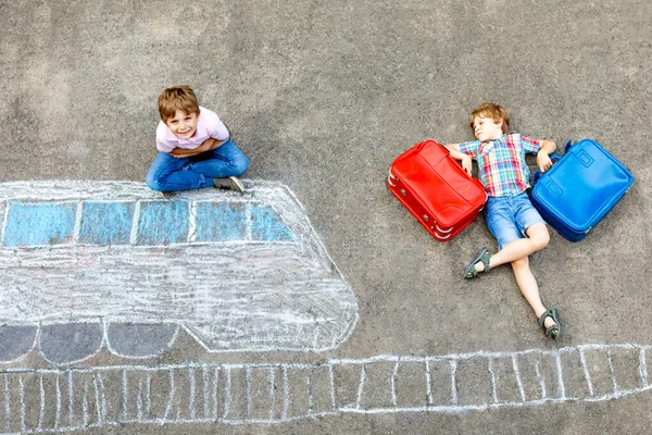 Due bambini piccoli che si divertono con il disegno del treno con gessetti colorati su asfalto. Bambini che si divertono con il gesso e la pittura a pastello. andare in vacanza e viaggiare. Amici con valigie — Foto Stock