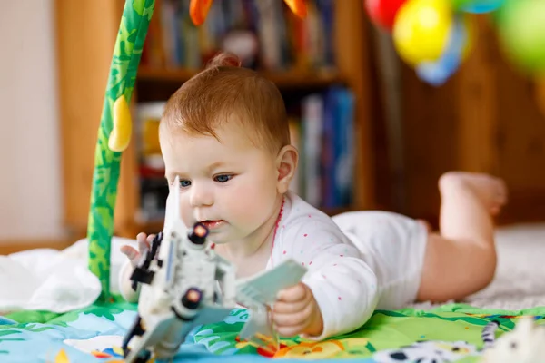 Härlig liten flicka leker med pedagogiska leksaker i barnkammaren. Glad frisk barn att ha kul med färgglada olika leksaker hemma. Söt baby lärande ta tag i saker och leksaker, sitta och krypa. — Stockfoto
