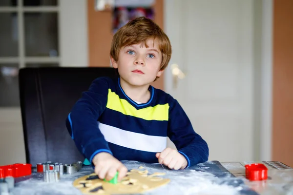 Lindo niño hornear galletas de jengibre de Navidad en casa. Adorable niño rubio divirtiéndose en la cocina doméstica. Ocio tradicional con niños en Navidad . — Foto de Stock