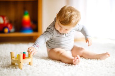 Eğitici oyuncaklarla oynayan sevimli bir kız bebek. Mutlu sağlıklı çocuk evde renkli tahta oyuncaklarla eğleniyor. Doğa oyuncağı olan çocuklar için erken gelişim.