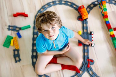 Renkli plastik bloklarla oynama ve tren istasyonu oluşturma sevimli küçük sarışın çocuk çocuk. Tren oyuncak ev bina ile eğleniyor çocuk